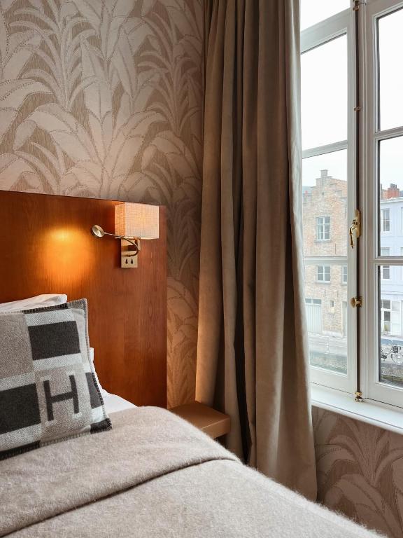 a bedroom with a bed and a window at Hotel Van Cleef in Bruges