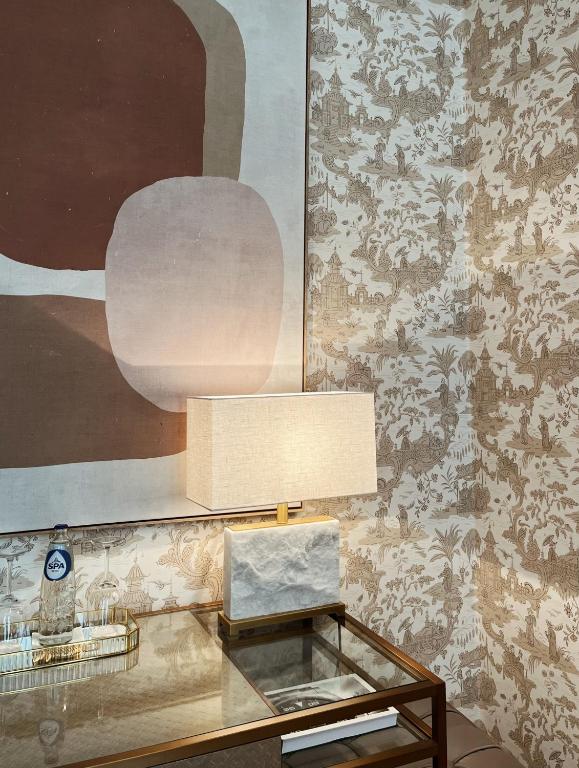 a glass table with a lamp and a wall at Hotel Van Cleef in Bruges