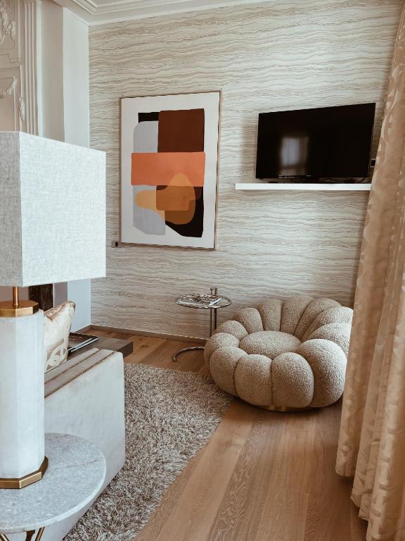 a living room with a round ottoman and a television at Hotel Van Cleef in Bruges