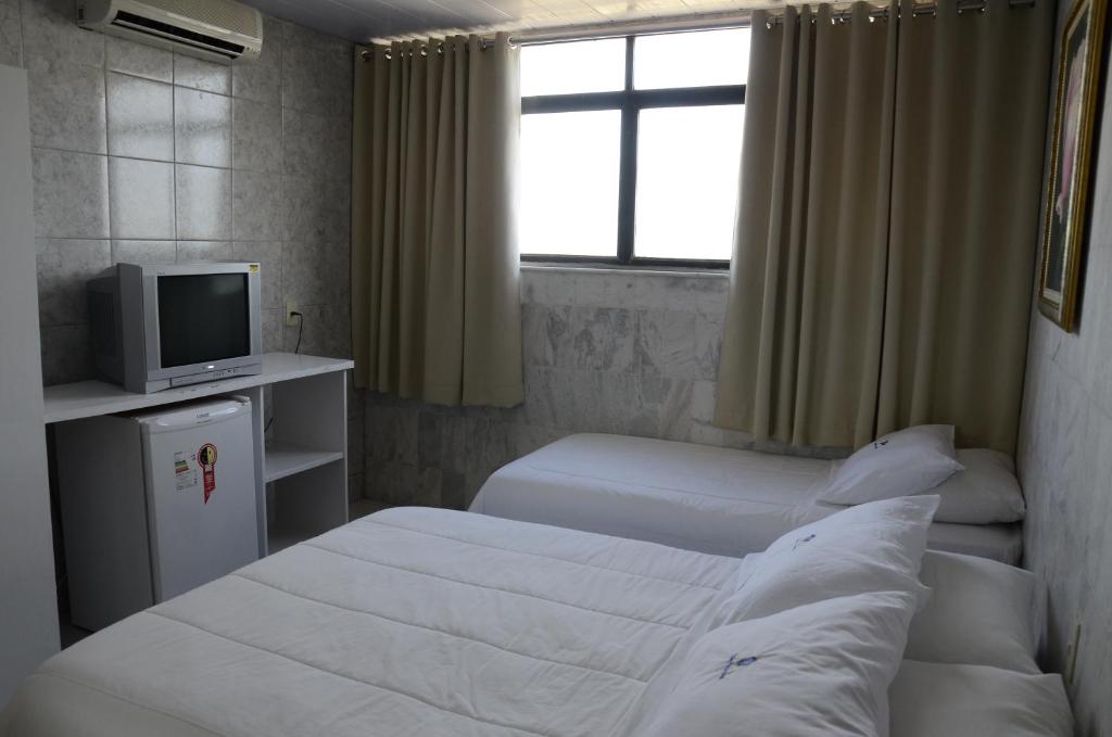 a hotel room with two beds and a television at Titão Plaza Hotel in Campina Grande