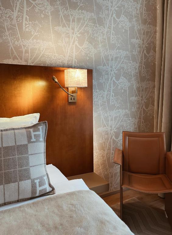 a bedroom with a bed and a lamp and a chair at Hotel Van Cleef in Bruges