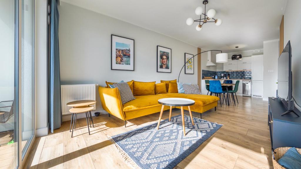 a living room with a yellow couch and a table at Apartamenty Sun & Snow Sagaris z basenem in Dziwnów