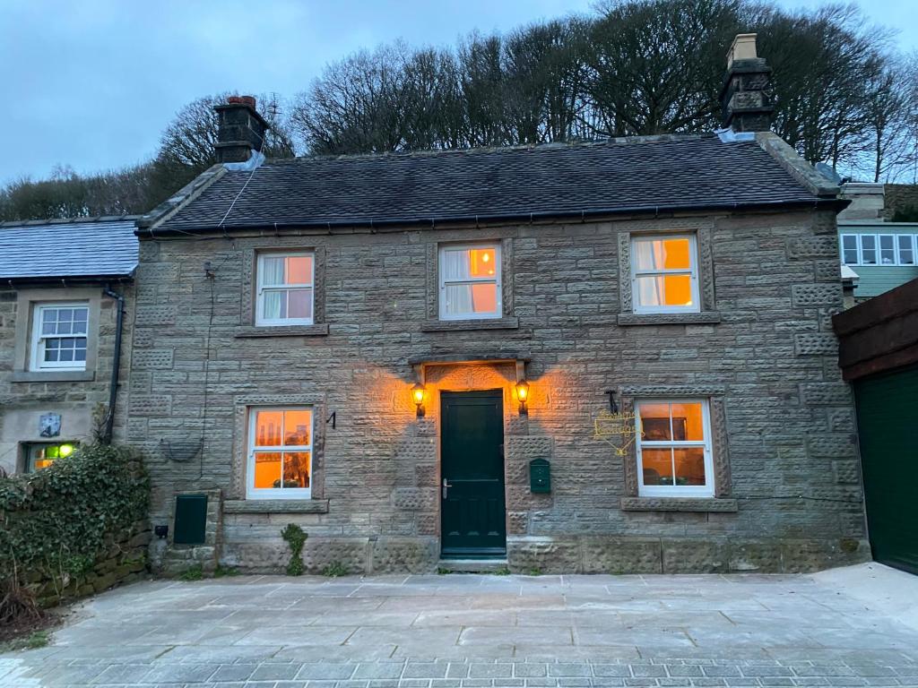 an old stone house with a driveway in front of it at Jasmine Cottage in Bakewell