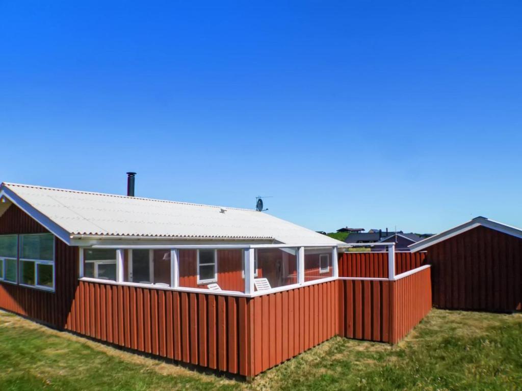 a house with a red fence in the grass at Holiday Home Dolma - 75m from the sea in NW Jutland by Interhome in Løkken