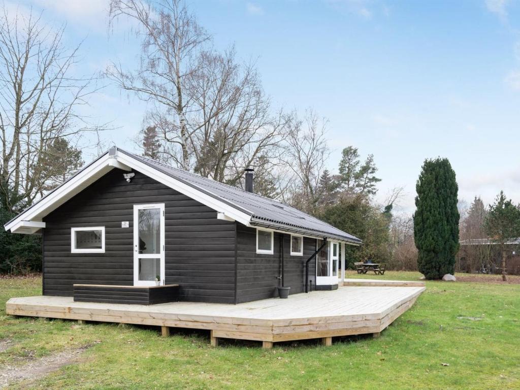 una pequeña casa negra con terraza de madera en Holiday Home Nannina - 225m to the inlet in Sealand by Interhome, en Frederiksværk