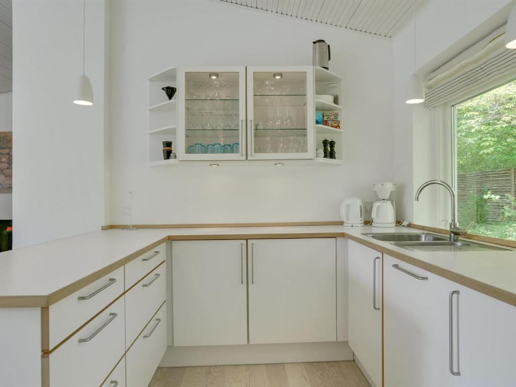 a white kitchen with white cabinets and a sink at Holiday Home Bjarne - 1-2km from the sea in Sealand by Interhome in Tisvildeleje