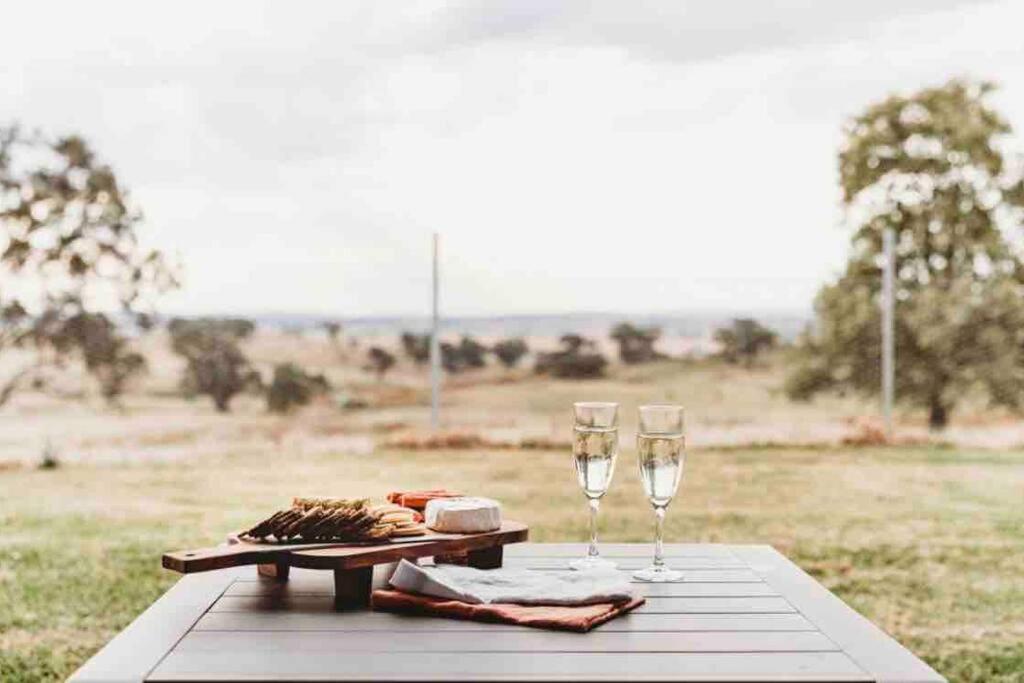 un tavolo con due bicchieri da vino e un piatto di cibo di The Oaks Country Getaway a Canowindra