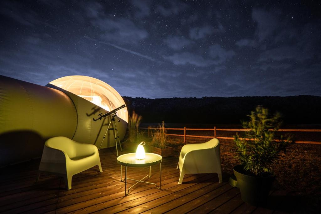 una mesa y sillas en una terraza por la noche en Bulle à la Belle étoile, en Clécy