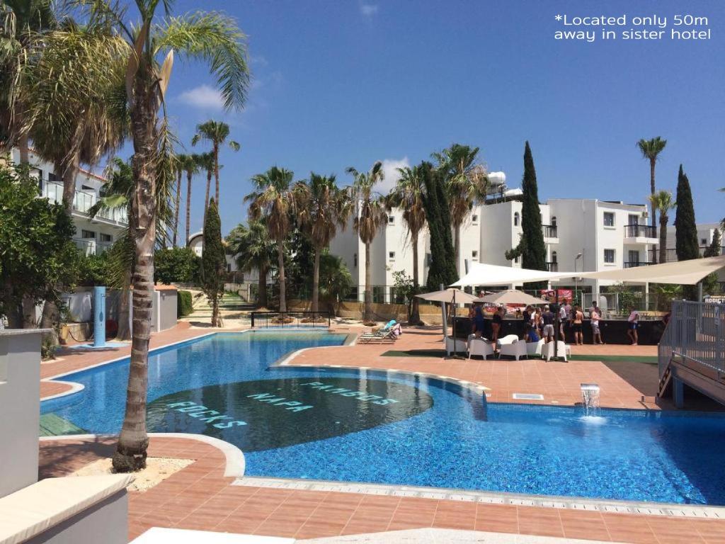 a large swimming pool with palm trees in a resort at Sant Central Deluxe Apartments in Ayia Napa