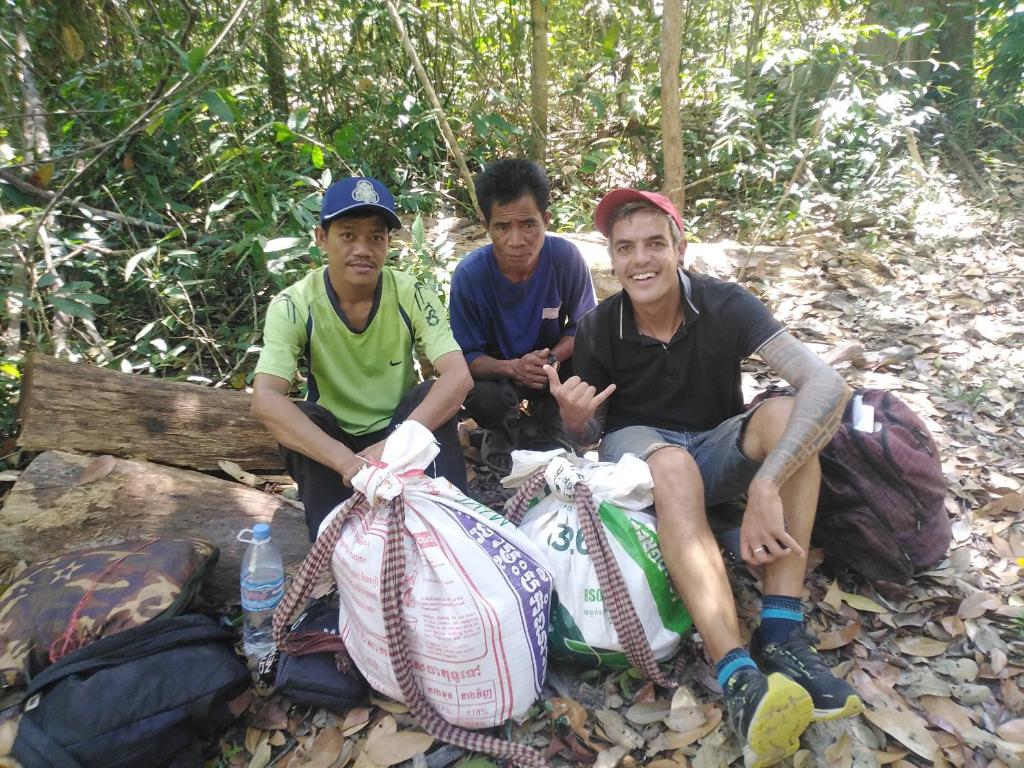 three men sitting on a bench with bags ofpacks at Reggae bar homestay& Sona trekking tour in Banlung
