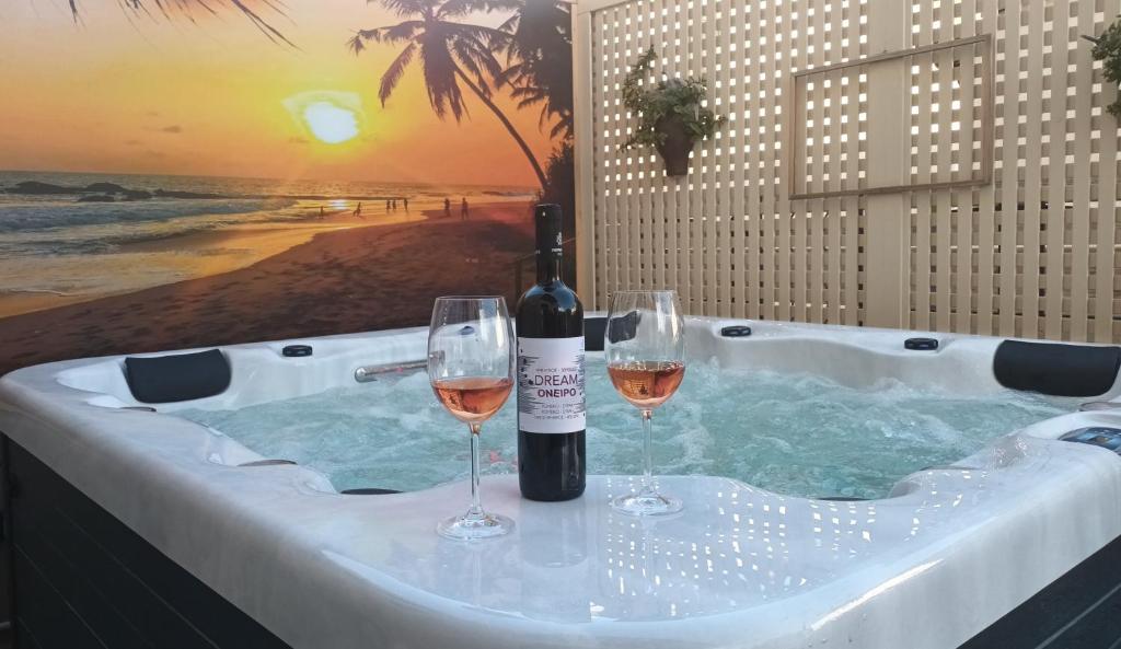 a hot tub with two wine glasses and a bottle of wine at Oneiro Residence in Petrokefálion