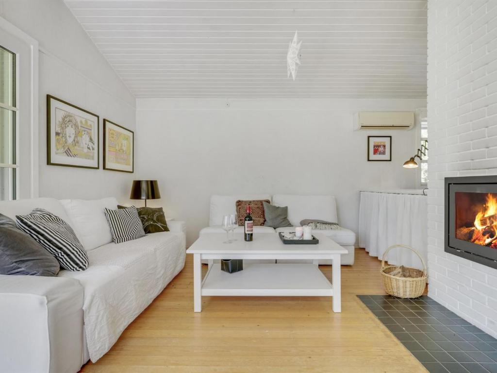 ein Wohnzimmer mit einer weißen Couch und einem Kamin in der Unterkunft Holiday Home Tobrjön - 200m to the inlet in Sealand by Interhome in Skibby