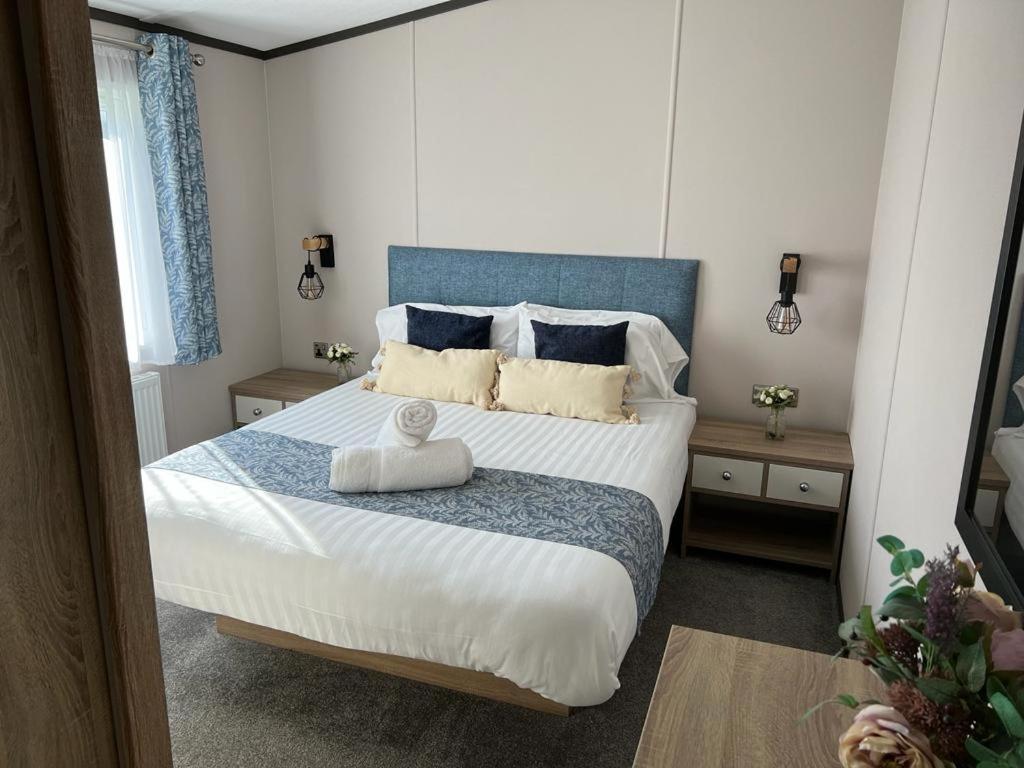 a bedroom with a large bed with a blue headboard at Darwin Lodge with Hot Tub in Malton