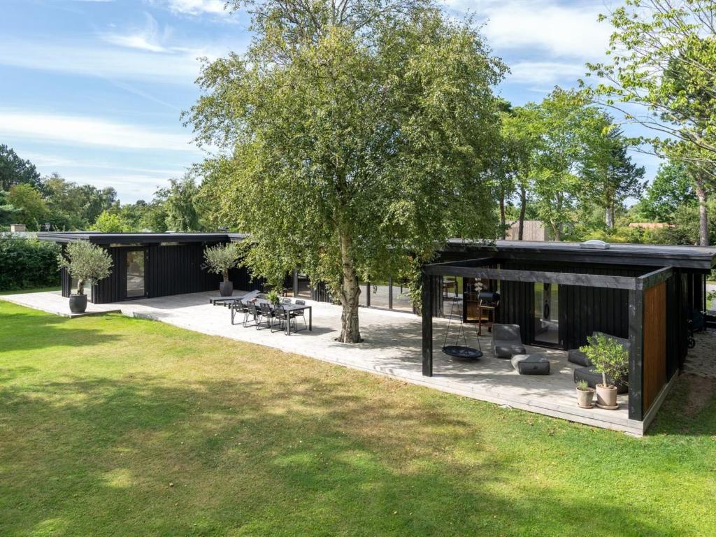 un patio esterno con un albero e una casa di Holiday Home Hævnir - 1km from the sea in Sealand by Interhome a Vejby