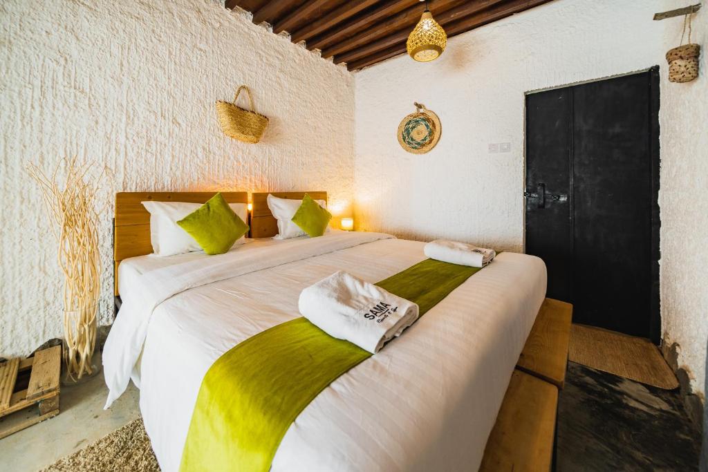 um quarto com uma cama grande com lençóis verdes e brancos em SAMA Al Khutaim-Heritage Home em Nizwa