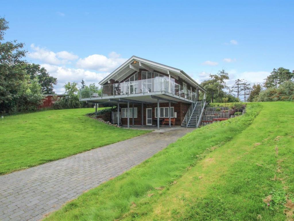 a large house on a grassy hill with a driveway at Holiday Home Vicente - 130m from the sea in Sealand by Interhome in Jægerspris