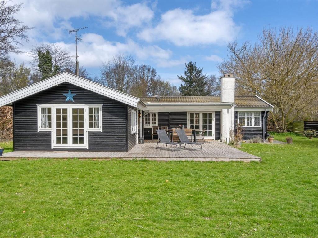a black house with a deck and a table and chairs at Holiday Home Hjort - 100m from the sea in Sealand by Interhome in Dronningmølle