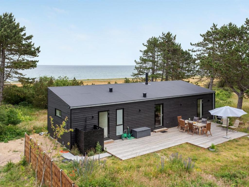 ein schwarzes Haus am Strand mit einer Terrasse in der Unterkunft Holiday Home Gjorgje - 100m from the sea in Sealand by Interhome in Tjørneholm