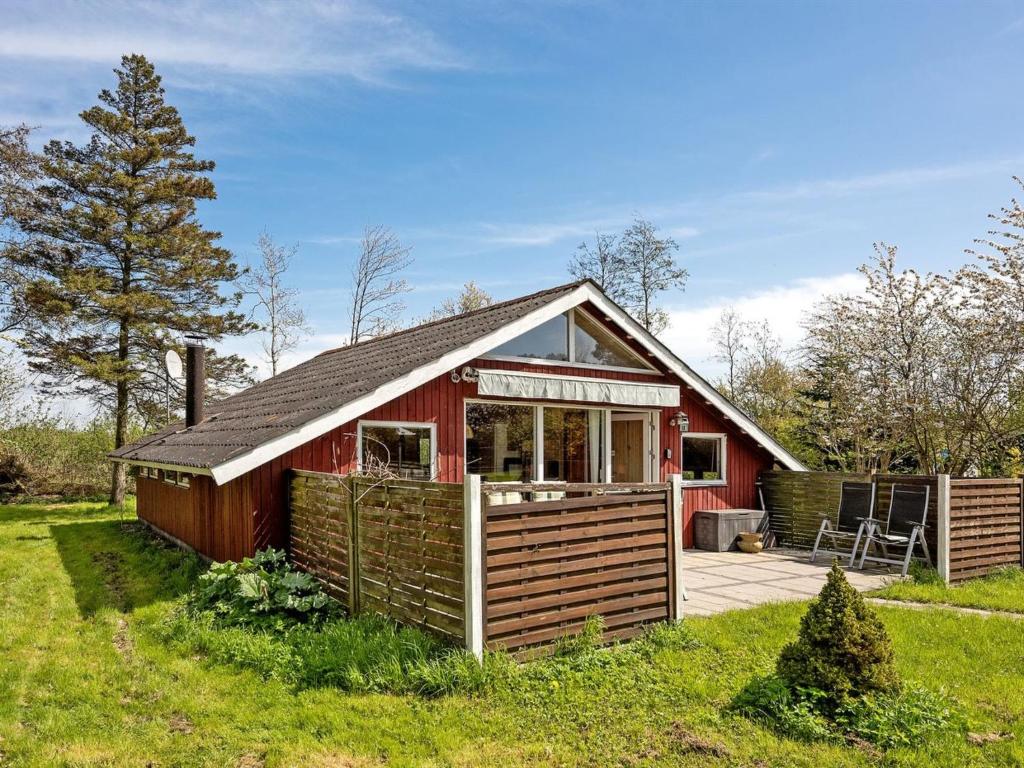 una casa roja con una terraza en el césped en Holiday Home Henna - all inclusive - 550m to the inlet by Interhome, en Vordingborg