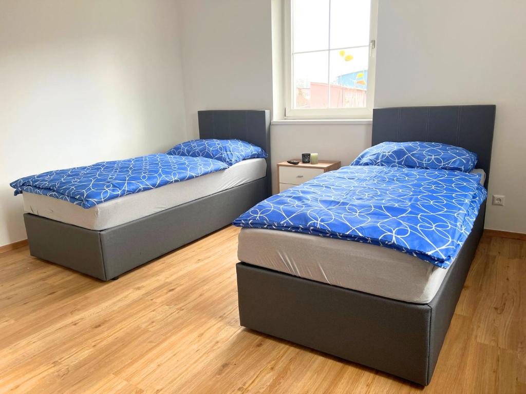two twin beds in a room with wood floors at Wochenzimmer - Premium Apartments für Monteure, Event- und Projektteams in Sankt Peter-Freienstein
