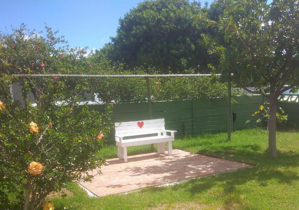 a white bench with a heart on it in a yard at Fisherhaven Guest House in Hermanus