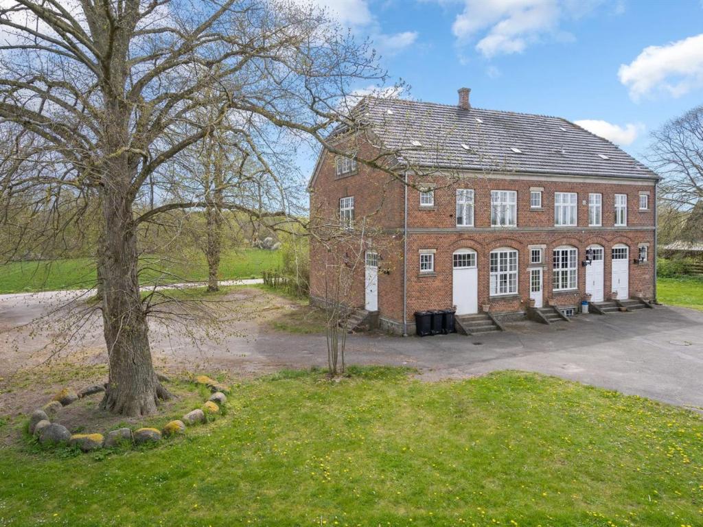 un viejo edificio de ladrillo con un árbol delante de él en Holiday Home Kadri in Sealand by Interhome, en Karise