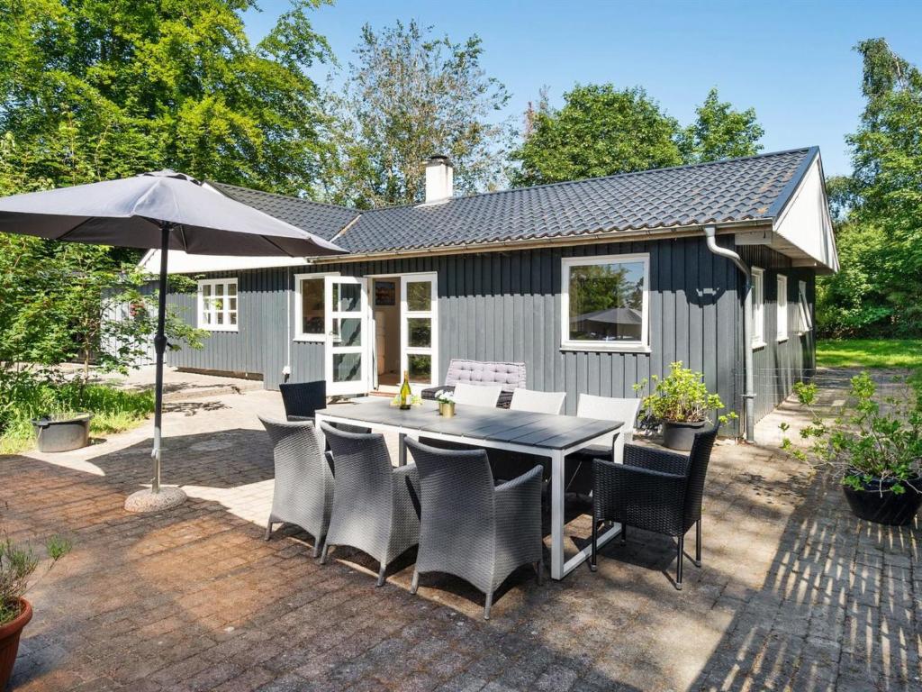 une terrasse avec une table, des chaises et un parasol dans l'établissement Holiday Home Tannie - 300m from the sea in Sealand by Interhome, à Strøby