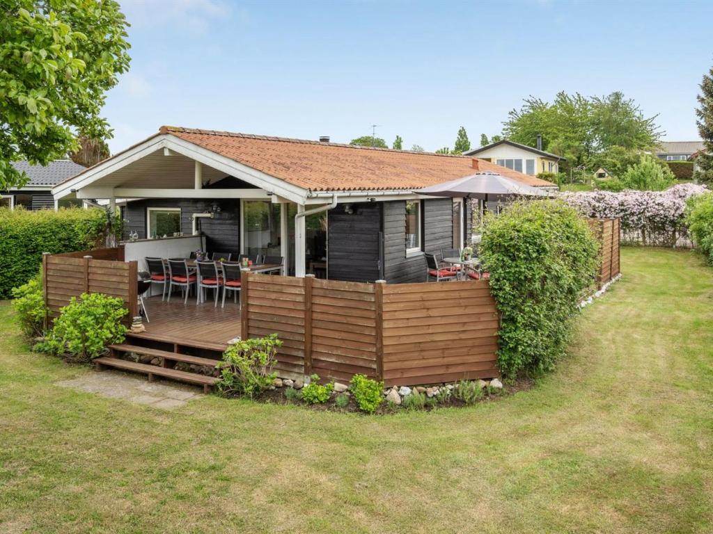 une maison avec une terrasse en bois dans la cour dans l'établissement Holiday Home Gisl - 400m from the sea in Funen by Interhome, à Bogense
