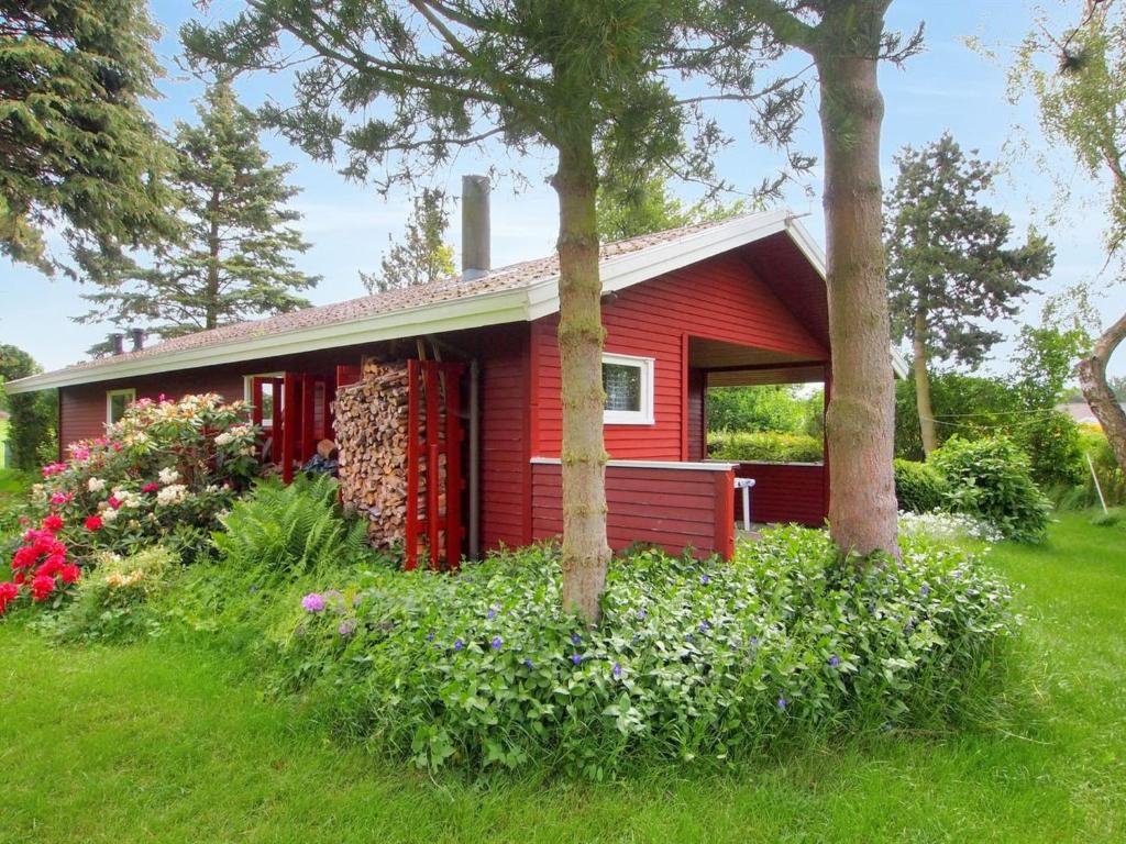 una pequeña casa roja con flores delante en Holiday Home Thing - 200m from the sea in Lolland- Falster and Mon by Interhome en Askeby