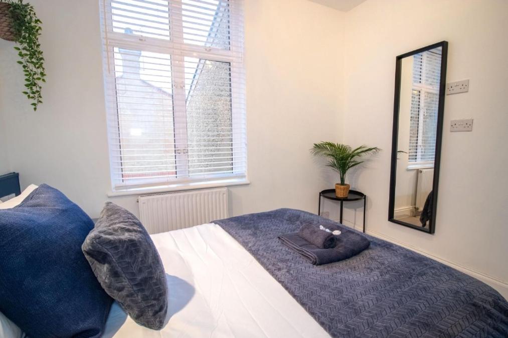 um quarto com uma cama com almofadas azuis e um espelho em SPACIOUS 3 Bed APARTMENT WITH EN-SUITES em Watford