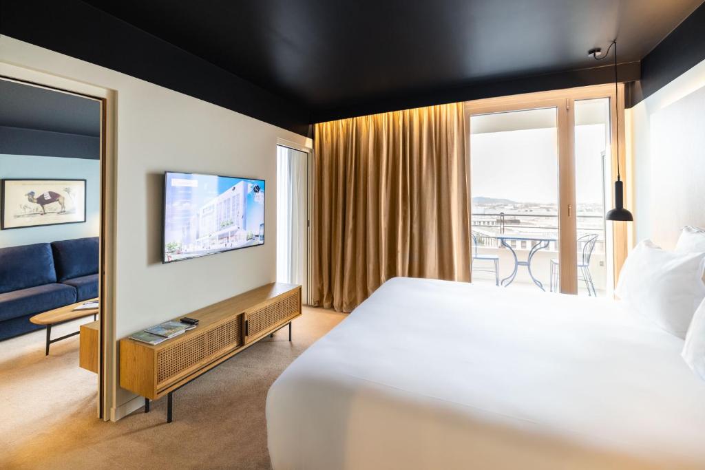 コロンブにあるKOPSTER Hotel Residence Paris Ouest Colombesのベッドとテレビが備わるホテルルームです。