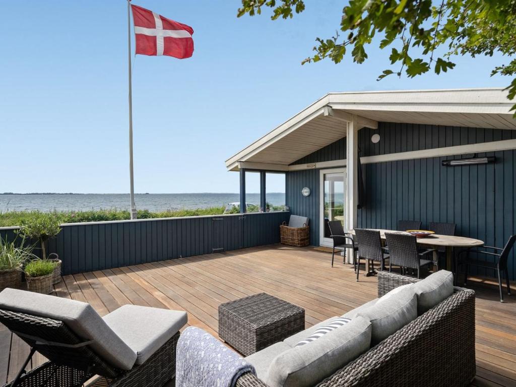 a deck with chairs and a table and a flag at Holiday Home Pellervo - 20m from the sea in Funen by Interhome in Assens