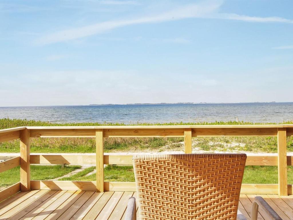 アッセンズにあるHoliday Home Bertold - 20m from the sea in Funen by Interhomeの海を見渡すデッキに座る籐の椅子