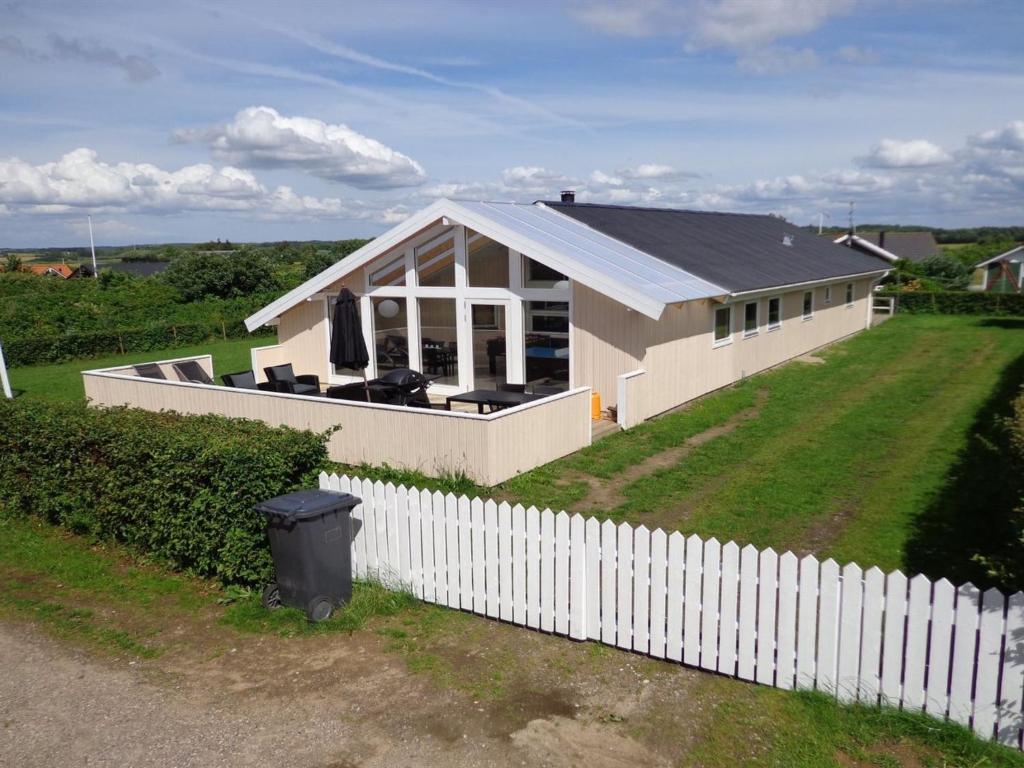 a white house with a white fence and a yard at Holiday Home Dunya - 400m from the sea in Funen by Interhome in Assens