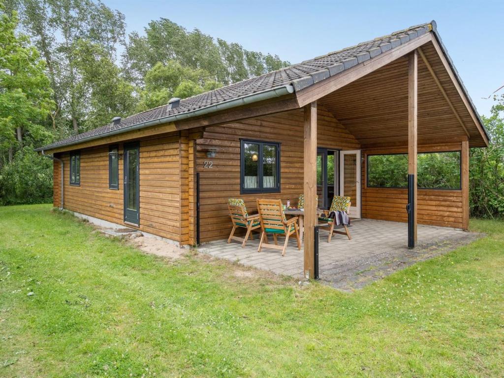 Ce chalet en bois dispose d'une terrasse avec une table et des chaises. dans l'établissement Holiday Home Rəzvan - 120m from the sea in Funen by Interhome, à Vedelshave