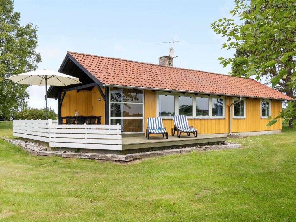 een geel huis met twee stoelen en een paraplu bij Holiday Home Janne - 400m from the sea in Funen by Interhome in Bogense