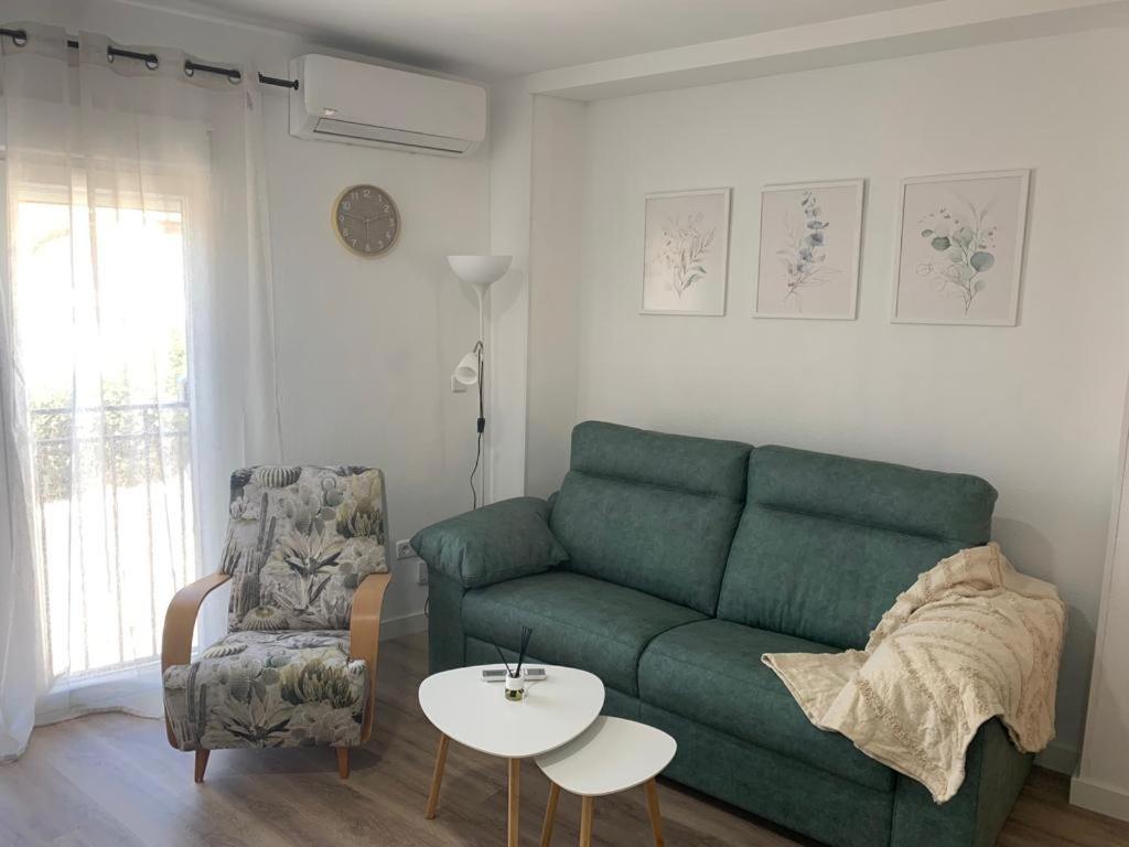 a living room with a green couch and a chair at Apartamento Peñas Blancas, junto a ruta de los Cahorros, Monachil. in Monachil