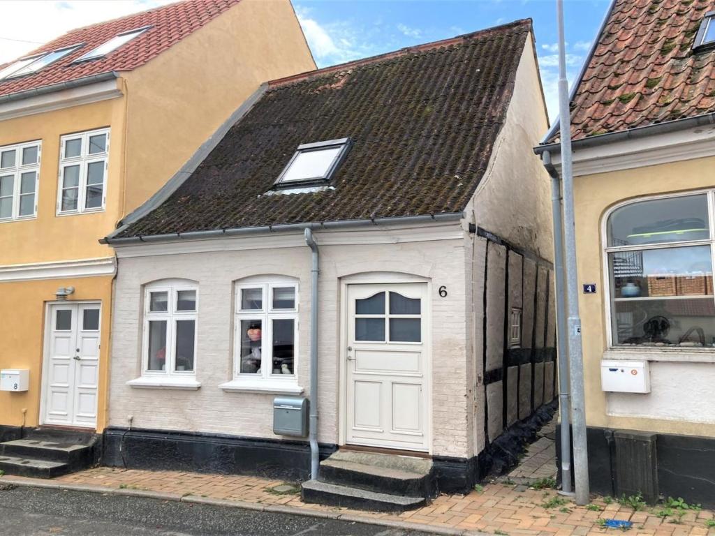 una pequeña casa blanca con techo marrón en Holiday Home Marilena - 300m from the sea in Funen by Interhome en Rudkøbing