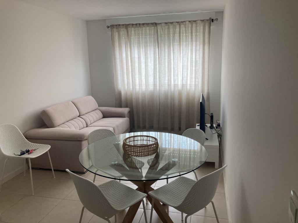 uma sala de estar com uma mesa de vidro e cadeiras em Casa da Marina em Esposende