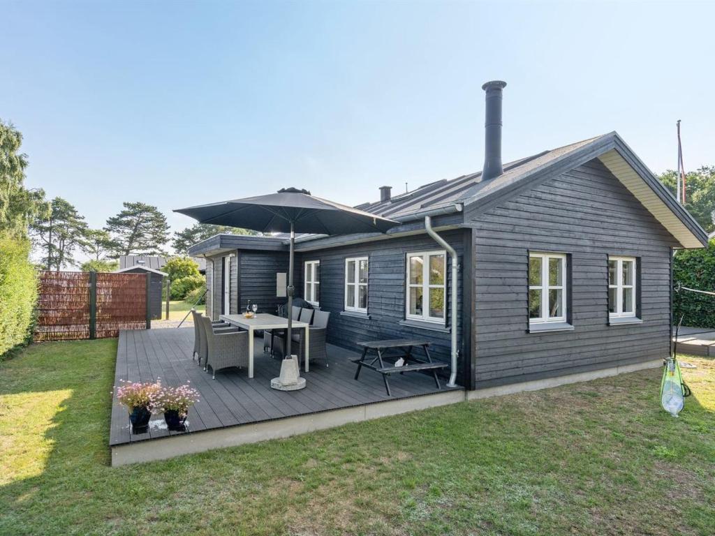 a small house with a deck with an umbrella at Holiday Home Kamilla - 200m from the sea in Funen by Interhome in Nyborg