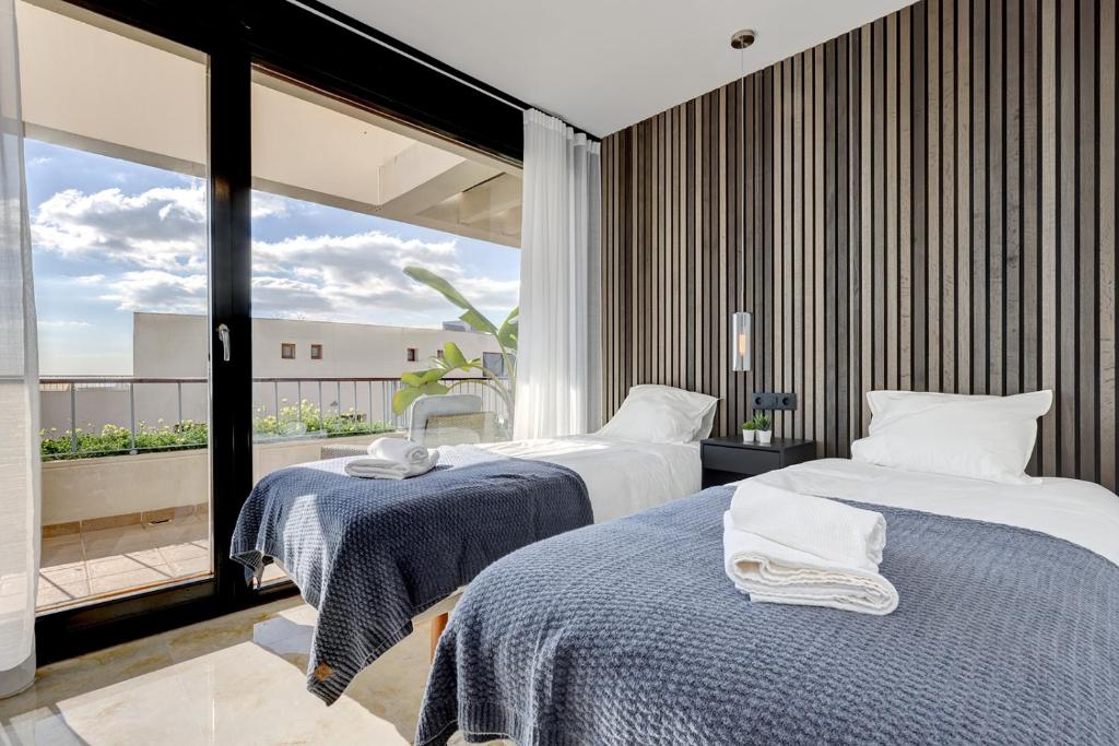 2 letti in una camera con una grande finestra di Modern, elite hillside home w/sea & mountain views a Marbella