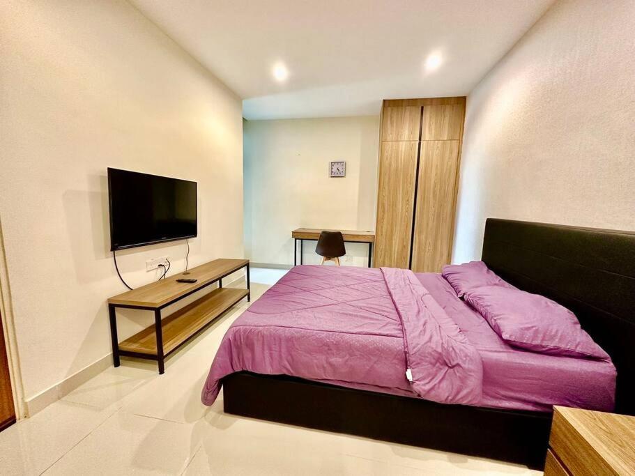 a bedroom with a purple bed and a flat screen tv at Kuching Kozi Square Apartment in Kuching