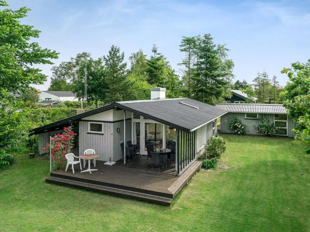 a small house with a deck in a yard at Holiday Home Juditha - 400m from the sea in Funen by Interhome in Middelfart