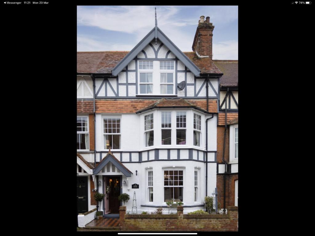 een wit huis met een zwart-witte gevel bij Albury House in Cromer