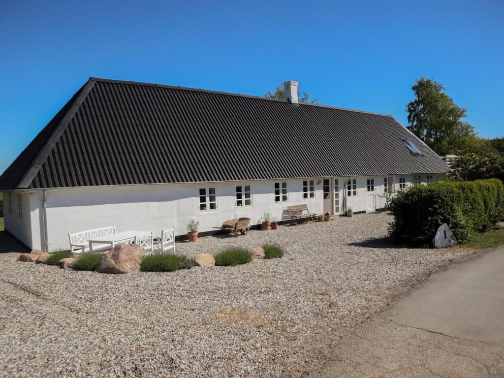 a white building with a black roof and benches at Holiday Home Harre - 300m from the sea in Funen by Interhome in Rudkøbing