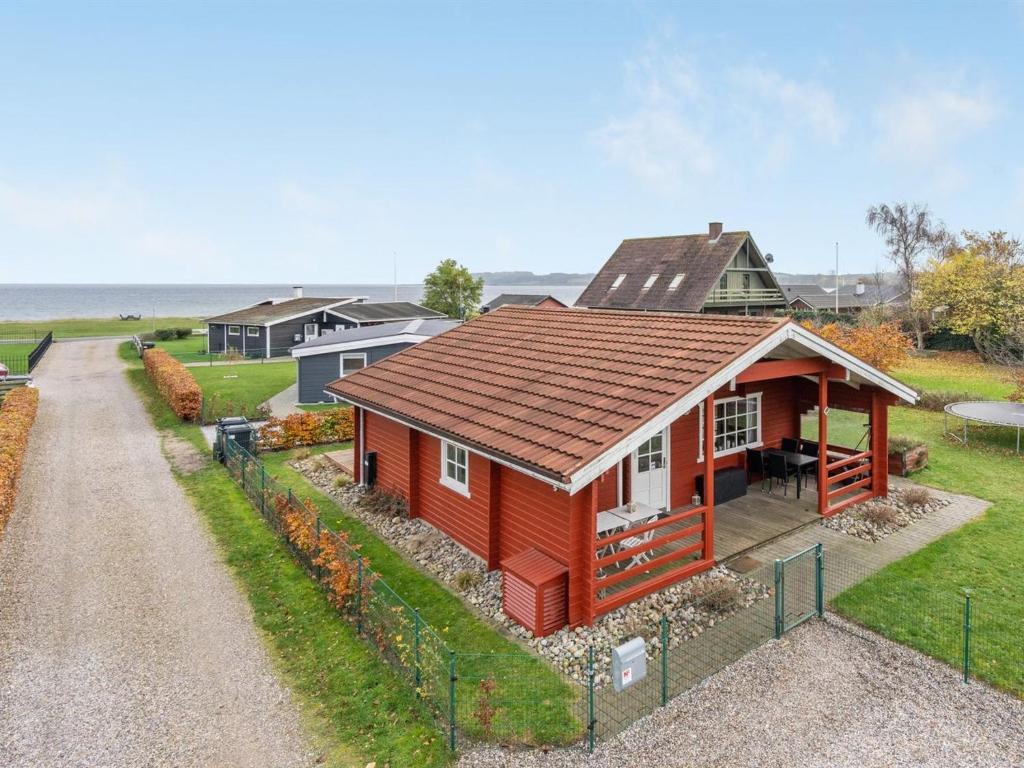 een klein rood huis met een bruin dak bij Holiday Home Baldo - 100m from the sea in SE Jutland by Interhome in Broager