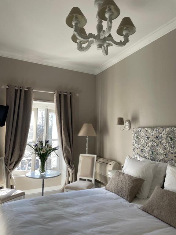 um quarto com uma cama, uma cadeira e um lustre em Hôtel Château des Jacobins em Agen