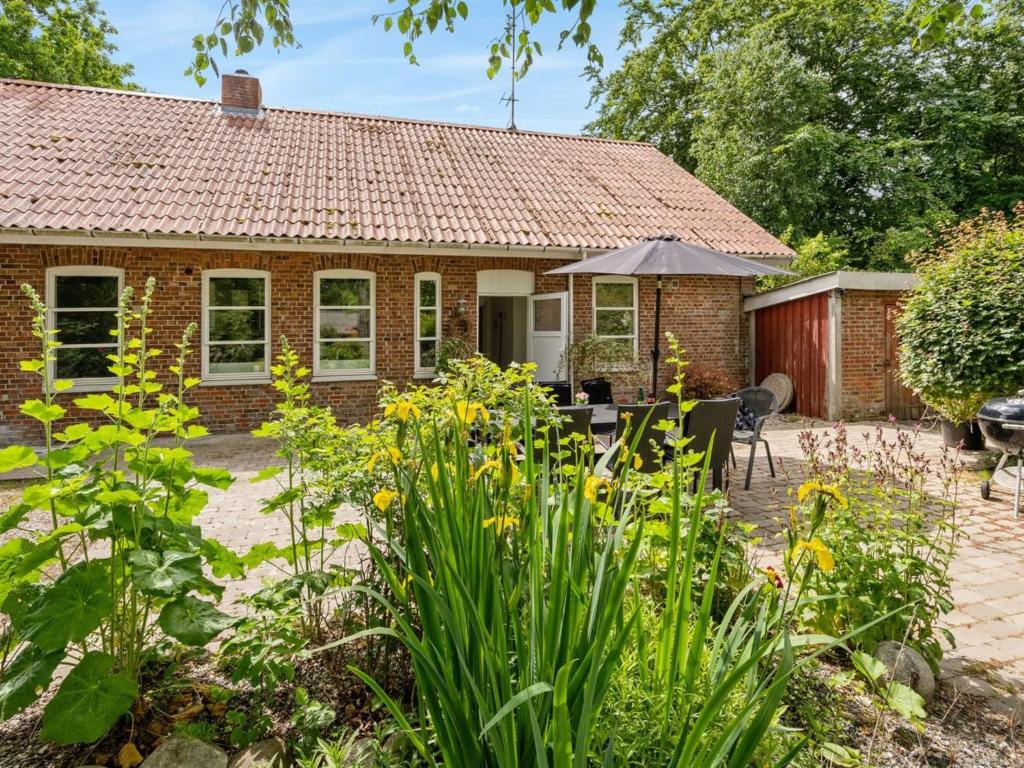 a brick house with a table and chairs in a garden at Holiday Home Jonni - 15km from the sea in Western Jutland by Interhome in Skærbæk