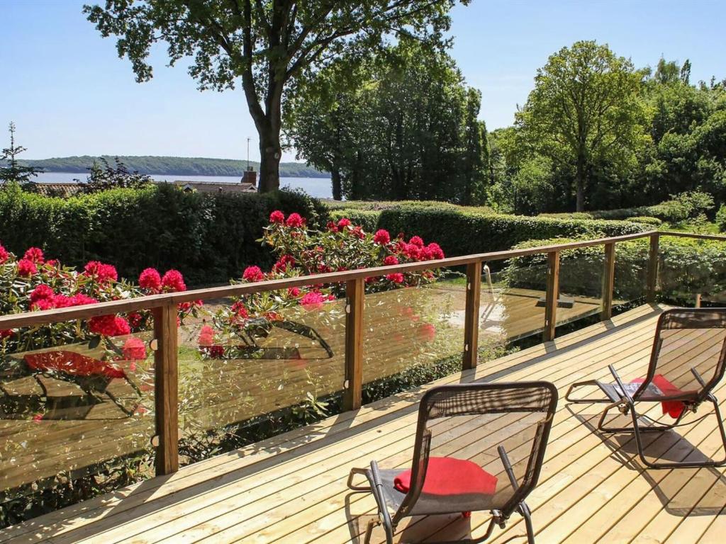 three chairs sitting on a deck with pink roses at Holiday Home Engelke - 150m from the sea in SE Jutland by Interhome in Kruså