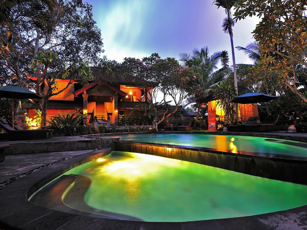 a swimming pool in front of a house at De Munut Balinese Resort in Ubud